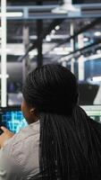Vertical Data center manager supervising worker deploying AI solutions optimizing equipment. Server farm supervisor overseeing programmer using artificial intelligence to minimize systems downtime, camera A video