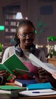 vertical multicultural alunos grupo discutindo uma financeiro projeto para uma universidade curso, usando computador portátil e livros didáticos com classe notas dentro a biblioteca. empreendedorismo e gestão habilidades. Câmera uma. video