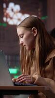 Vertical Intellectual college student researching public relations and its societal impact, utilizing laptop and educational materials from the library archives to complete a class assignment. Camera A. video
