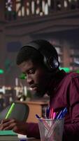 Vertical Black guy using study music to help with deep focus for academic success, consulting the campus university database to find reliable sources. Male college student fights for diploma. Camera B. video