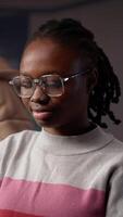 Vertical Black girl studying in university library for her bachelor degree diploma, using the educational research collection and general database for knowledge. Collecting citations for paper. Camera A. video