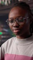 Vertical Black girl studying in university library for her bachelor degree diploma, using the educational research collection and general database for knowledge. Collecting citations for paper. Camera B. video