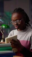 Vertical African american girl does bachelor paper research for citations and other information, using the database at the campus library. Intelligent student working on her diploma. Camera A. video