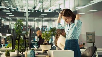 Upset worker in office packing desk plants on last day at work after quitting, saying goodbye to colleague. Employee getting fired from job during layoffs, saddening coworkers, camera B video