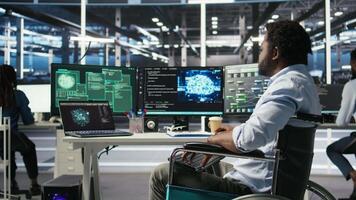 Data center engineer in wheelchair using AI requesting help from coworkers during security breach. Server farm worker with disability aided by colleagues to fight hacker attack stealing data, camera A video