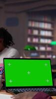 Vertical College student looks at a copy space on laptop while collecting notes from reliable academic sources, consulting the campus library books collection for an assignment. Student life. Camera A. video