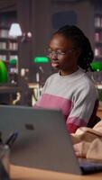 Vertical Female student reading and writing detailed notes for an exam, studying political science for upcoming lecture in a library setting at the university. Young adult consults a colleague. Camera A. video