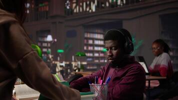 African american guy student uses ambient focus music to help with school assignment, collecting citations from books and other academic sources from the university database. Camera B. video