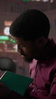 Vertical African american guy studies for a critical law exam and reading specialty books to complete class notes with reliable academic information. Studying in the library before the test. Camera B. video
