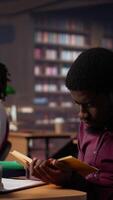 Vertical African american guy highlighting essential handwritten class notes to integrate in diploma paper with citations from academic sources within the library database. Research collection. Camera A. video
