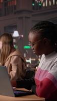 Vertical University student making exam preparations with a friend at the campus library, doing research to complete handwritten class notes. Girls sharing information from the database. Camera B. video