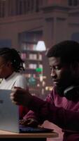 Vertical African american male student completes textbook with handwritten class notes, reading information from specialty books at the university library. Young adult consulting database. Camera A. video