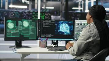 Server farm IT expert responds to security breach alert displayed on computer monitor, working to secure hardware. Data center employee attempts to protect equipment during cyberattack, camera B video