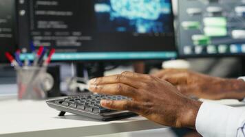Data center computer scientist at desk using AI deep learning algorithms to analyze datasets. Server room IT specialist typing on PC keyboard, using artificial intelligence neural networks, camera B video