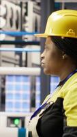 Vertical Technician in industrial plant monitors production equipment using PC software, diagnosing malfunctions. Factory employee coordinates repair tasks on assembly lines using computer program, camera B video