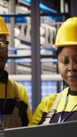 Vertical Solar panels factory team working together to fix gear, following maintenance procedures. Photovoltaics plant coworkers doing brainstorming, analyzes data on laptop to predict failures, camera A video
