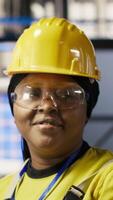 Vertical Portrait of smiling technician in industrial plant overseeing solar energy installation process. Happy worker in renewable energy manufacturing facility calibrating automated robotic arms, camera B video