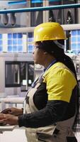 Vertical Portrait of cheerful factory engineer typing on PC, overseeing monitoring of production lines. Jolly woman in industry 4.0 plant ensuring machinery operates at optimal efficiency, camera A video
