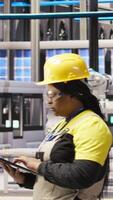 Vertical Smart factory engineer using laptop to implement automated workflows and control systems, computerizing operations. Technician integrates sensors into production using notebook, camera A video