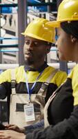 Vertical Manager overseeing work done by engineer in smart factory, ensuring quality control during manufacturing. Team leader supervising employee monitoring automated conveyor systems, camera A video