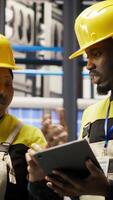 Vertical Engineering team working together in industry 4.0 plant to diagnose malfunctions. Teamworking factory colleagues coordinating repair tasks on manufacturing assembly lines, camera B video