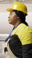 Vertical Technician walking in industrial plant, using toolbox to diagnose and fix equipment errors. African american woman in manufacturing factory coordinates repair tasks on assembly lines, camera B video