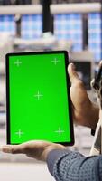Vertical Photovoltaics plant worker uses chroma key notebook to follow maintenance procedures. Solar panels factory engineer analyzes performance data with isolated screen laptop, camera A close up video