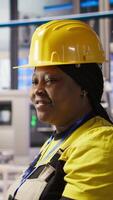 Vertical Happy engineer in smart photovoltaics factory looking at system performance metrics. Smiling worker in solar panels plant tracking energy production through IoT sensors, camera A video