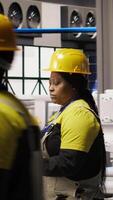 Vertical Technician in eco friendly industrial plant monitors production equipment using notebook, diagnosing malfunctions. Factory employee coordinates repair tasks on solar panels assembly line, camera A video