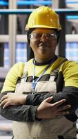 Vertical Portrait of smiling technician in industrial plant working to diagnose equipment errors. Jolly manufacturing factory professional coordinating repair tasks on assembly lines, camera B video
