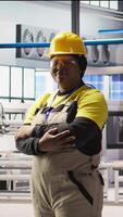 Vertical Portrait of smiling technician in industrial plant working to diagnose equipment errors. Jolly manufacturing factory professional coordinating repair tasks on assembly lines, camera A video