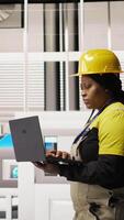 Vertical Specialist using laptop to conduct routine inspections in industry 4.0 plant producing renewable energy. Technician in photovoltaics smart factory testing equipment using notebook, camera A video