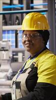 Vertical Portrait of smiling technician in industrial plant overseeing solar energy installation process. Happy worker in renewable energy manufacturing facility calibrating automated robotic arms, camera A video