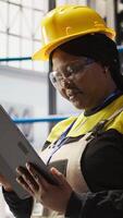Vertical Solar panels plant expert uses tablet to oversee systems, ensuring machinery operates at optimal efficiency. Photovoltaics plant employee uses device software to maintain operations, camera A close up video