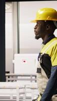 Vertical Man walking in industry 4.0 plant, taking note of modifications to make, providing technical support. Smart factory serviceman adding IoT sensors monitoring energy consumption, camera A video