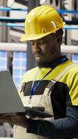Vertical Smart factory specialist, testing automated systems, monitoring production performance. Industry 4.0 plant technician inspecting machinery to identify and optimize bottlenecks, camera B video
