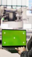 Vertical Specialist using green screen laptop to conduct inspection in renewable energy industry 4.0 plant. Technician in photovoltaics smart factory testing equipment using chroma key notebook, camera B video