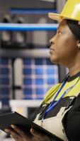 Vertical Smart manufacturing factory engineer using tablet app to calibrate high tech machinery and analyze sensor data. Engineer using digital device to troubleshoot photovoltaic assembly equipment, camera B video