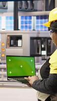 Vertical Engineer in photovoltaics factory using chroma key laptop to look at system performance metrics. Worker in industry 4.0 plant using green screen mockup notebook to track energy production, camera A video