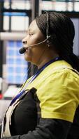 Vertical Call center agent in smart factory using headset to assist remotely with maintenance queries, monitoring automated solar panel assembly processes, providing technical guidance, camera B video