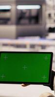 Vertical Industrial plant technician uses isolated screen tablet to implement green energy solutions, integrating solar tech in systems. Factory worker enhancing production efficiency using mockup device video