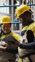 Vertical Solar panels factory engineering team analyzes performance data on laptop to predict gear failures. Teamworking photovoltaics plant colleagues following maintenance procedures, camera A video