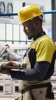 Vertical Engineer in smart factory does maintenance using laptop software, analyzing IoT sensor data. Industry 4.0 plant worker managing operational reliability of photovoltaic systems using notebook, camera A video