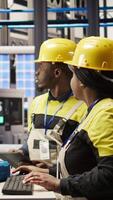 Vertical Smart factory manager overseeing work done by engineer calibrating high tech machinery and analyzing sensor data. Team leader supervising engineer troubleshooting assembly equipment, camera A video