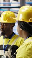 Vertical Manager supervising technician in industrial plant using PC software to diagnose malfunctions. Factory team leader working with coworker to coordinate repair tasks on assembly lines, camera B video