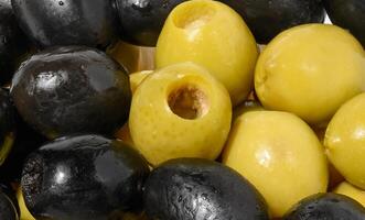 Detailed close up mix of smooth, pitted green and black olives, filling the frame photo