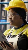 Vertical Smart factory engineer using tablet to analyze IoT sensors data, refining equipment operational efficiency. Industrial plant worker performs system diagnostics to reduce production downtime, camera B video