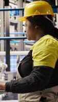 Vertical Technician in industrial plant monitors production equipment using PC software, diagnosing malfunctions. Factory employee coordinates repair tasks on assembly lines using computer program, camera A video
