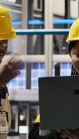 Vertical Engineering team working together in photovoltaics factory, looking at system performance metrics. Teamworking colleagues in industry 4.0 plant track energy production through IoT sensors, camera B video