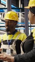 Vertical Manager supervising technician in industrial plant using PC software to diagnose malfunctions. Factory team leader working with coworker to coordinate repair tasks on assembly lines, camera A video